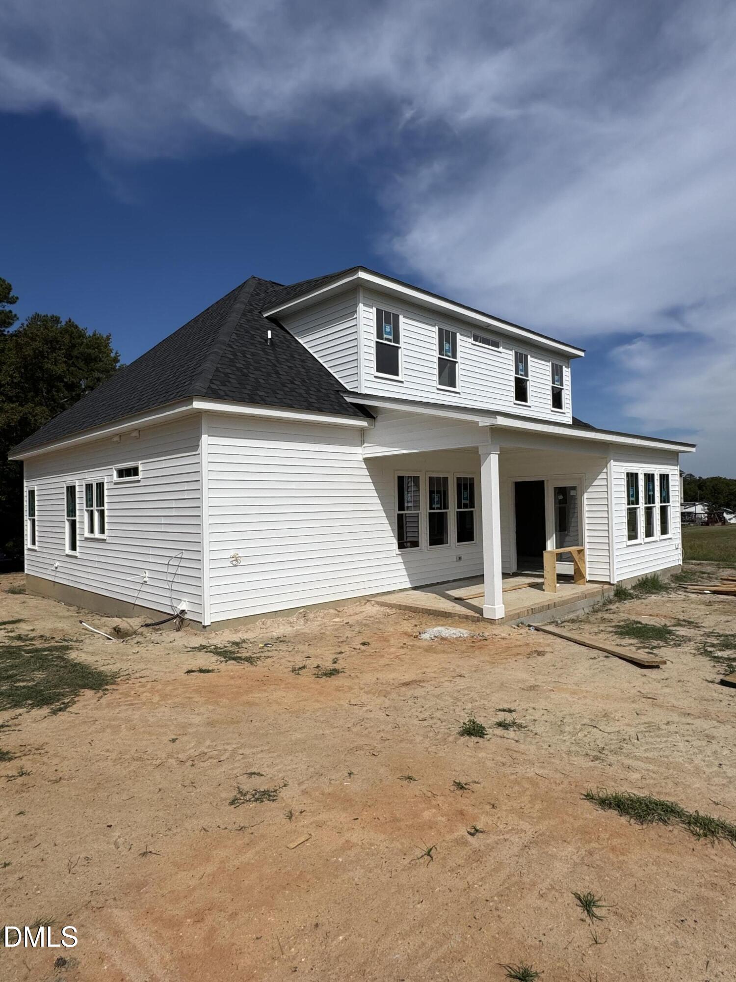 Two-story white-sided house with a covered porch and unfinished dirt yard.