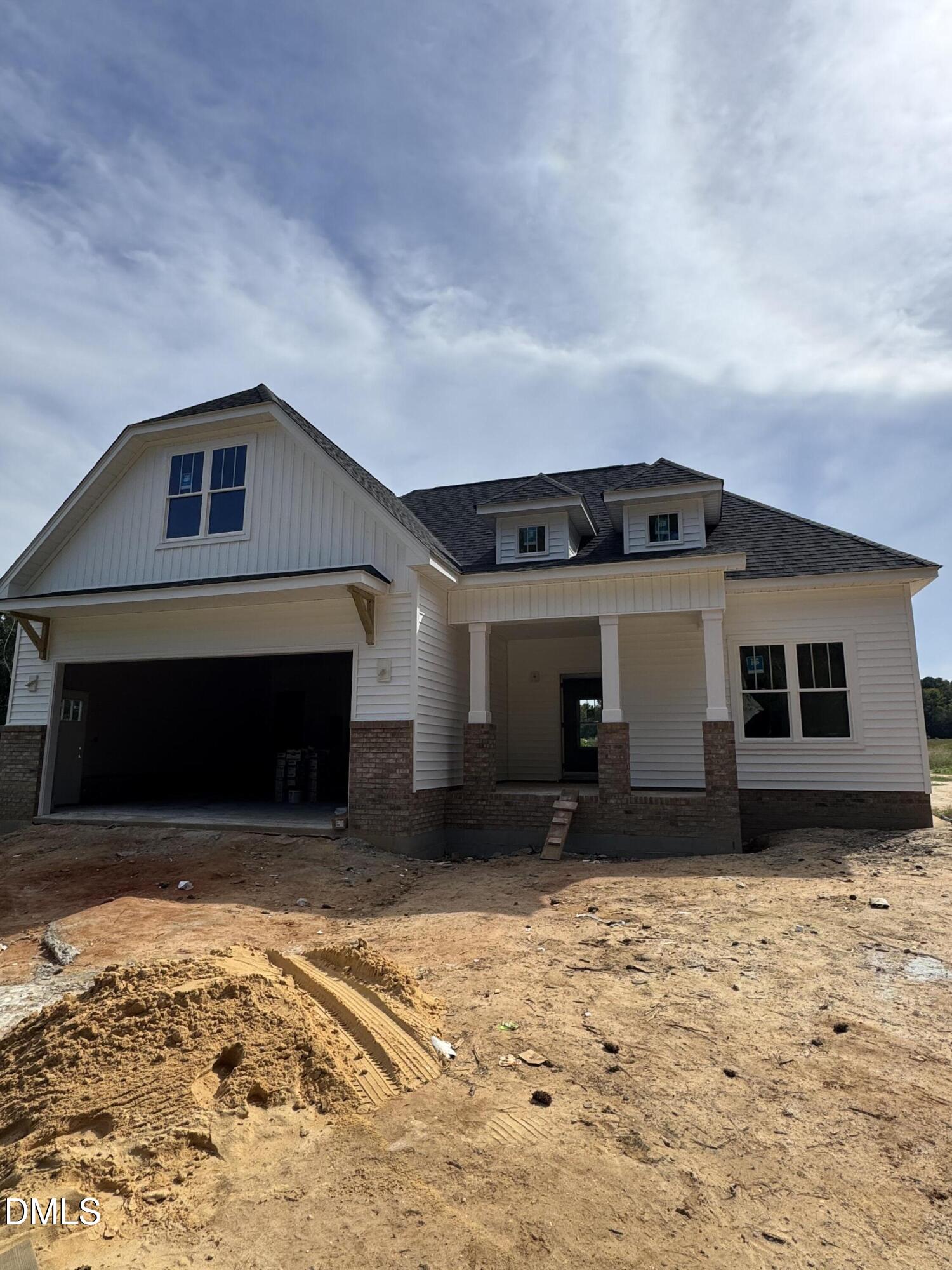 White-sided house under construction with a double garage and covered front porch.
