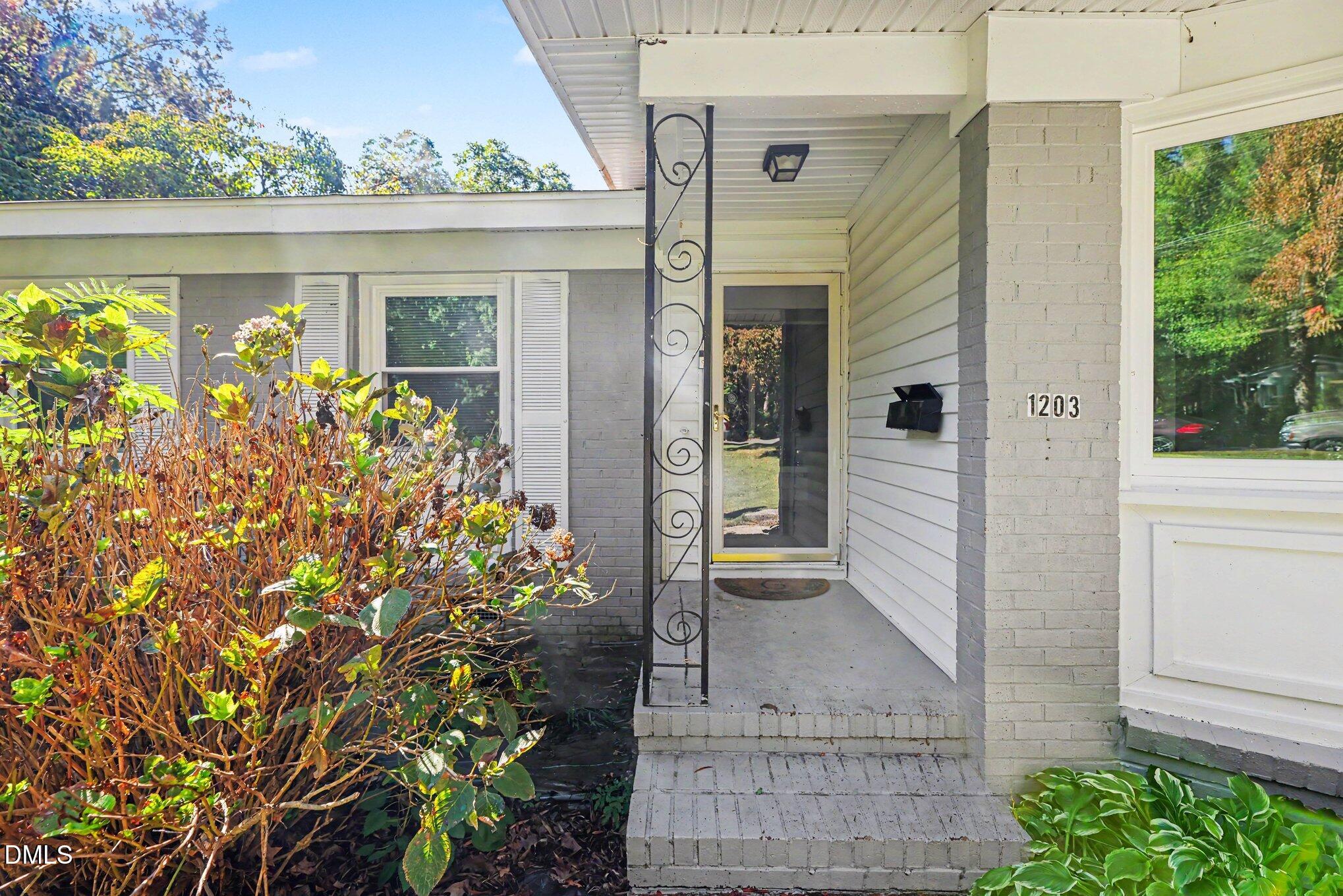 Home entrance with a brick porch, decorative metal post, and address number 1203.