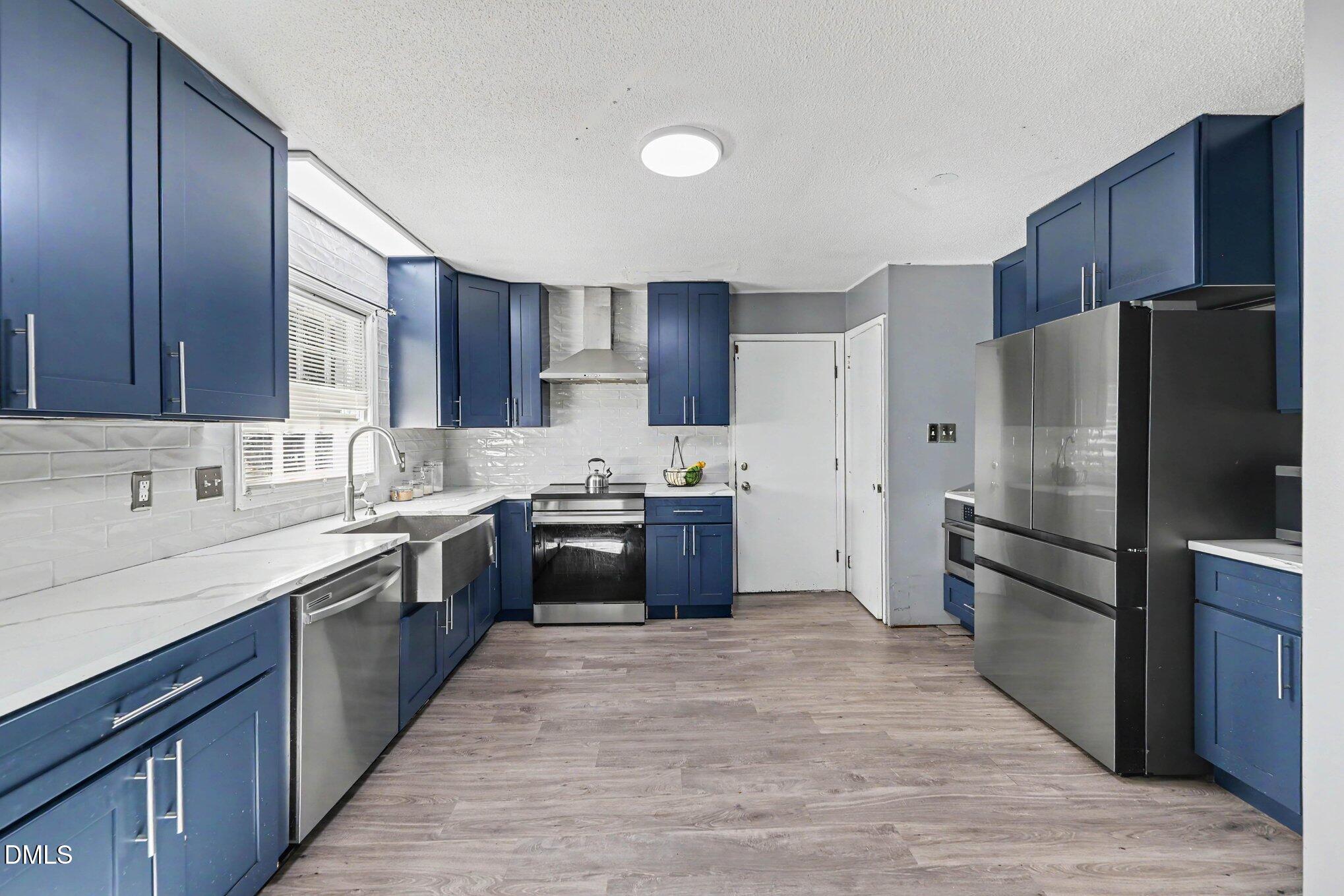 Kitchen with navy-blue cabinets, white countertops, and stainless-steel appliances.