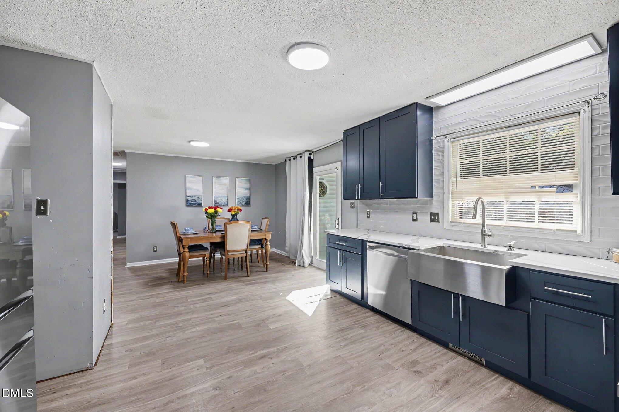 Kitchen with navy cabinets, stainless farmhouse sink, and an adjacent dining area.
