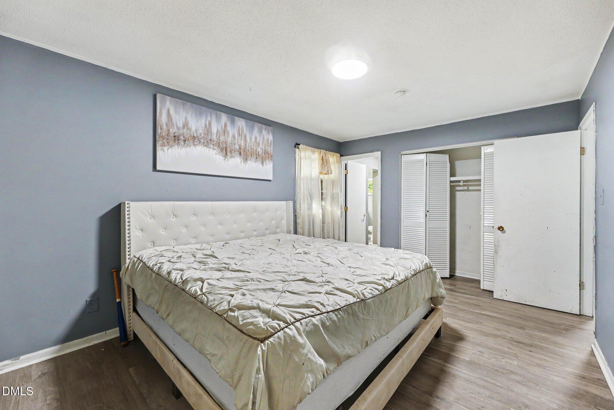 Bedroom with a large white bed, gray walls, and an open closet.