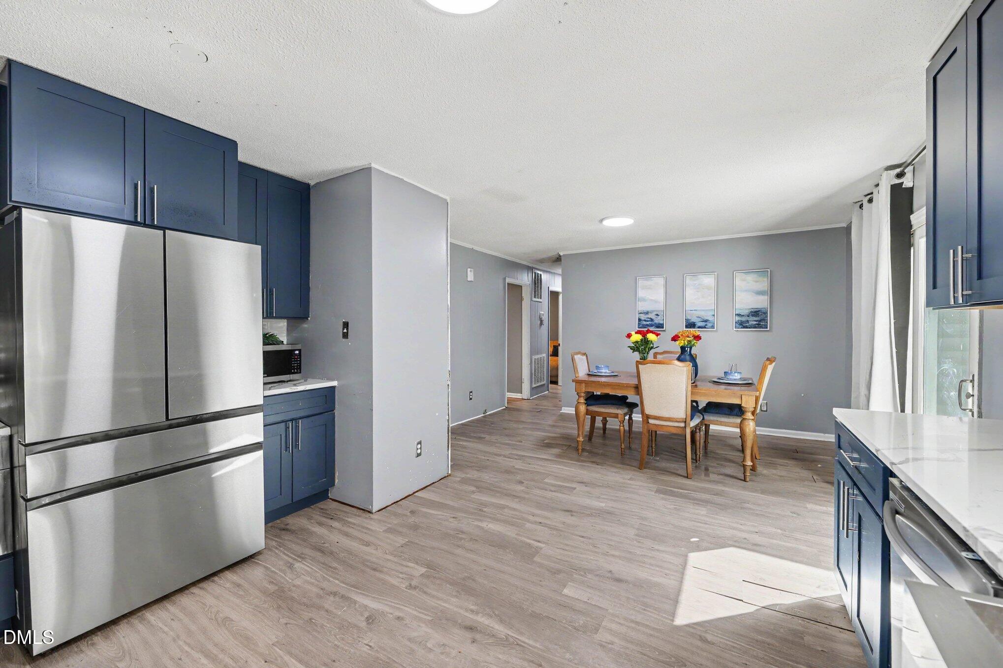 Kitchen and dining area with navy cabinets, stainless steel appliances, and a set dining table.