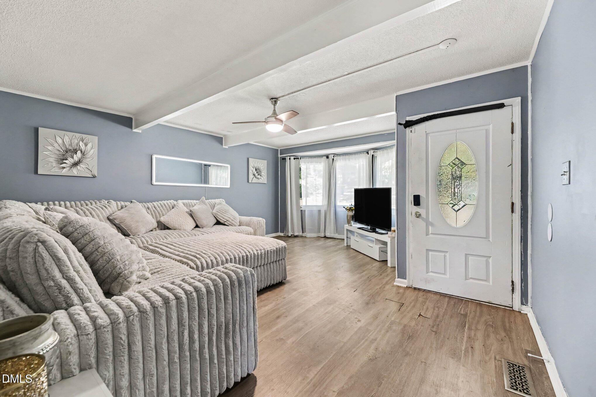 Living room with a plush gray sectional, wood-look flooring, and a glass-panel front door.