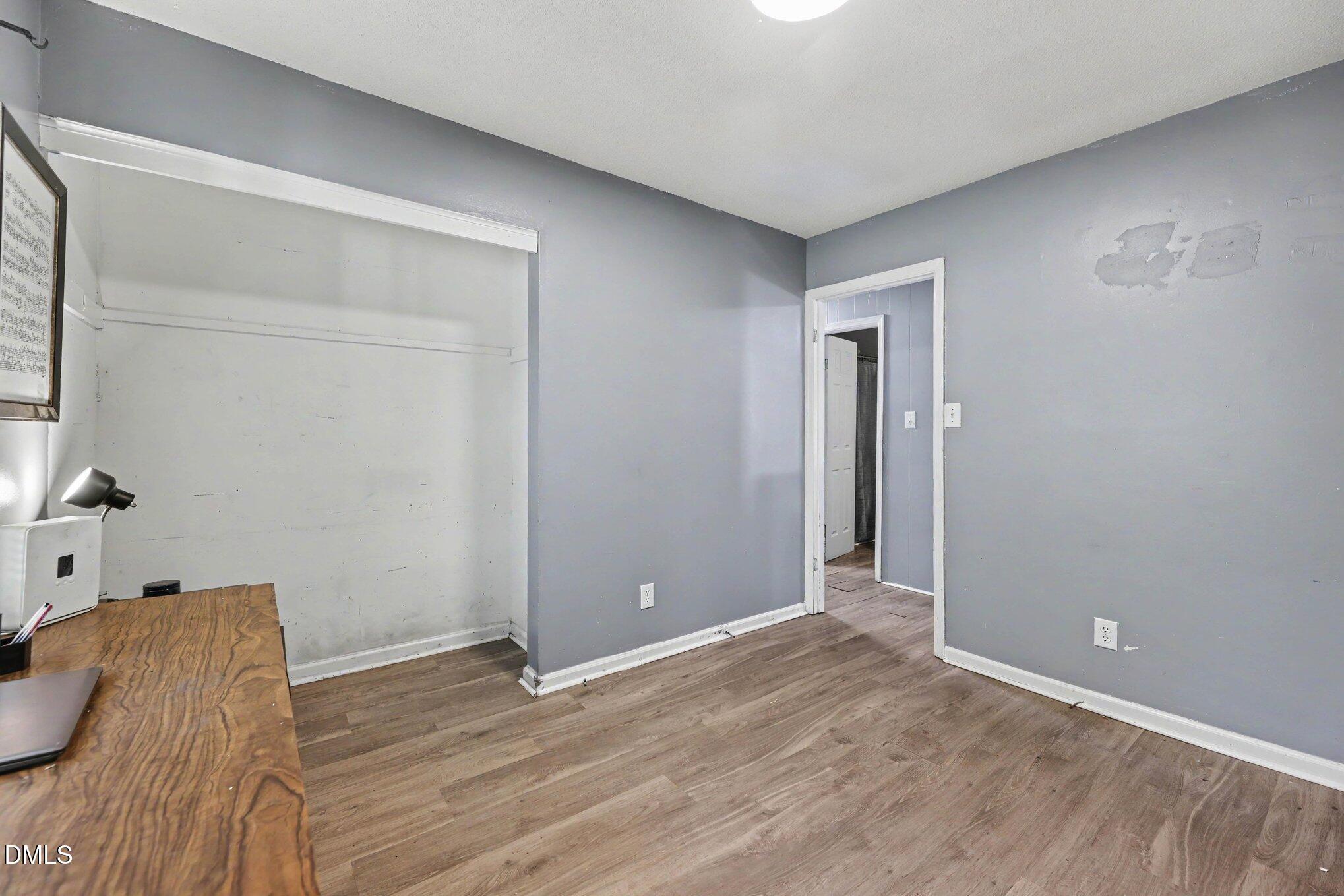 Office with built-in shelving, a wooden desk, gray walls, and wood-look flooring.