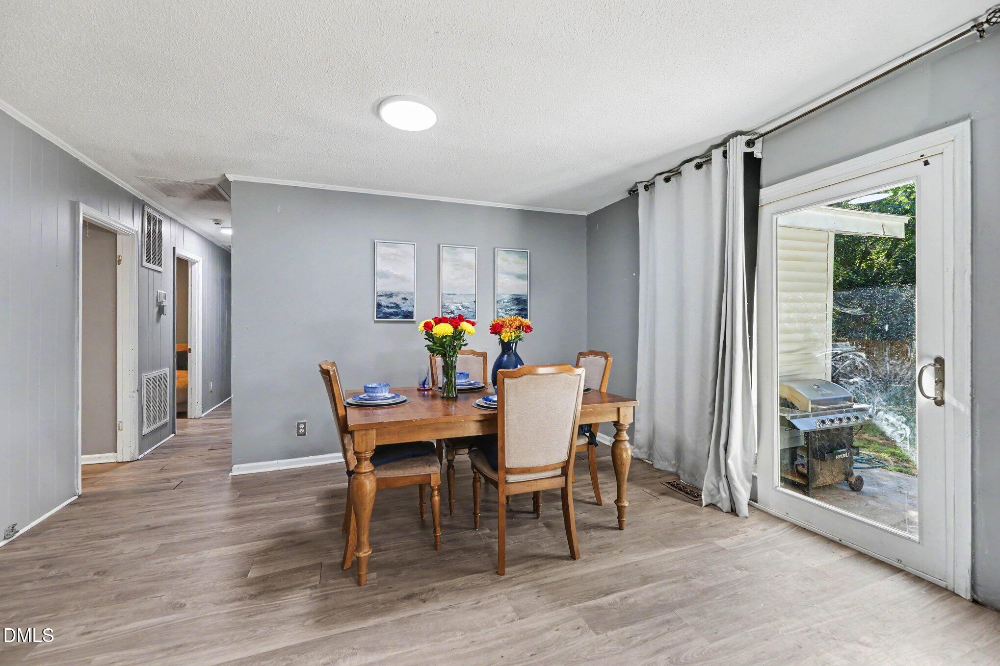 Dining room with a wood table, upholstered chairs, and a glass door opening to the yard.