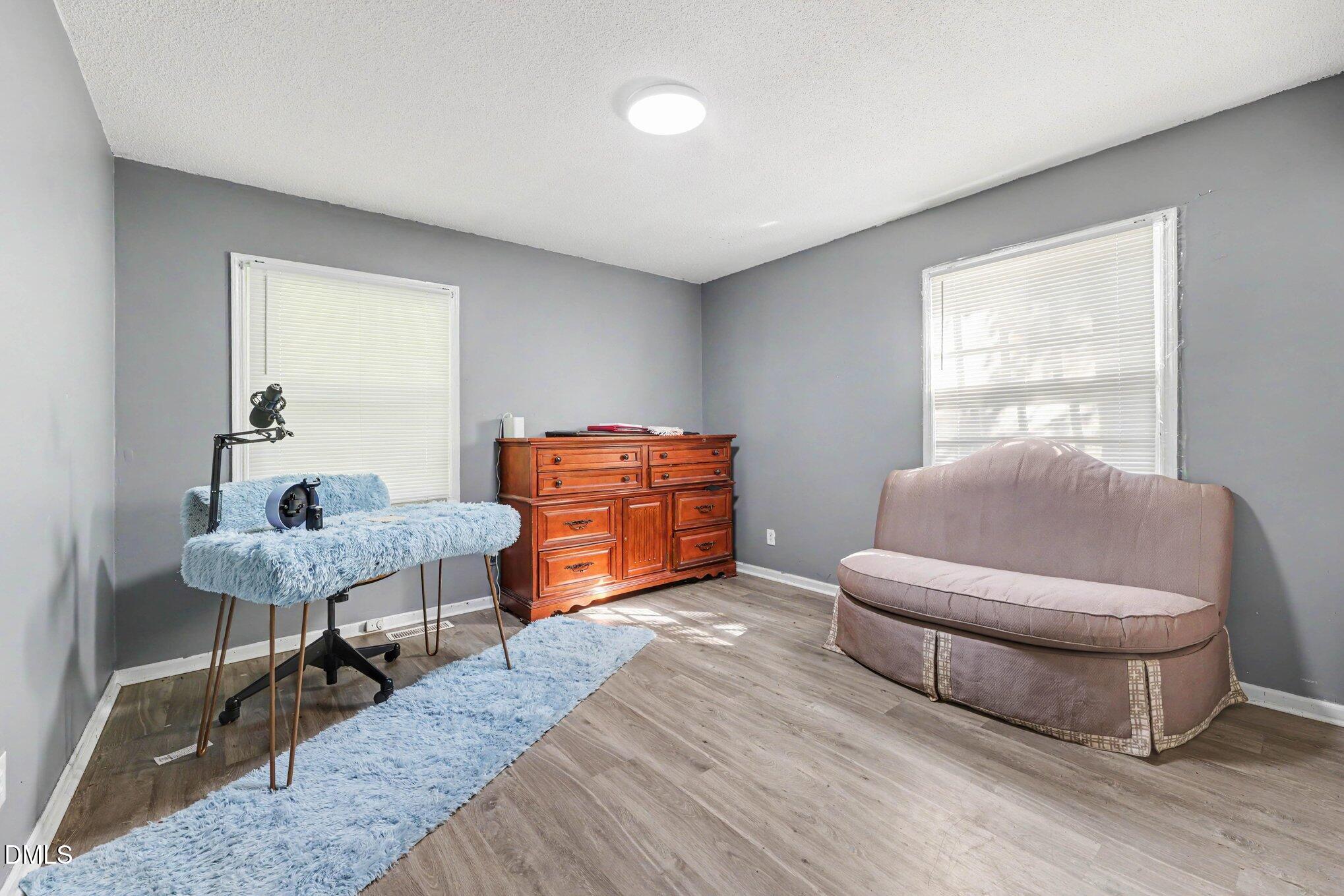 Furnished bedroom with gray walls, a wooden dresser, and a blue shag rug.