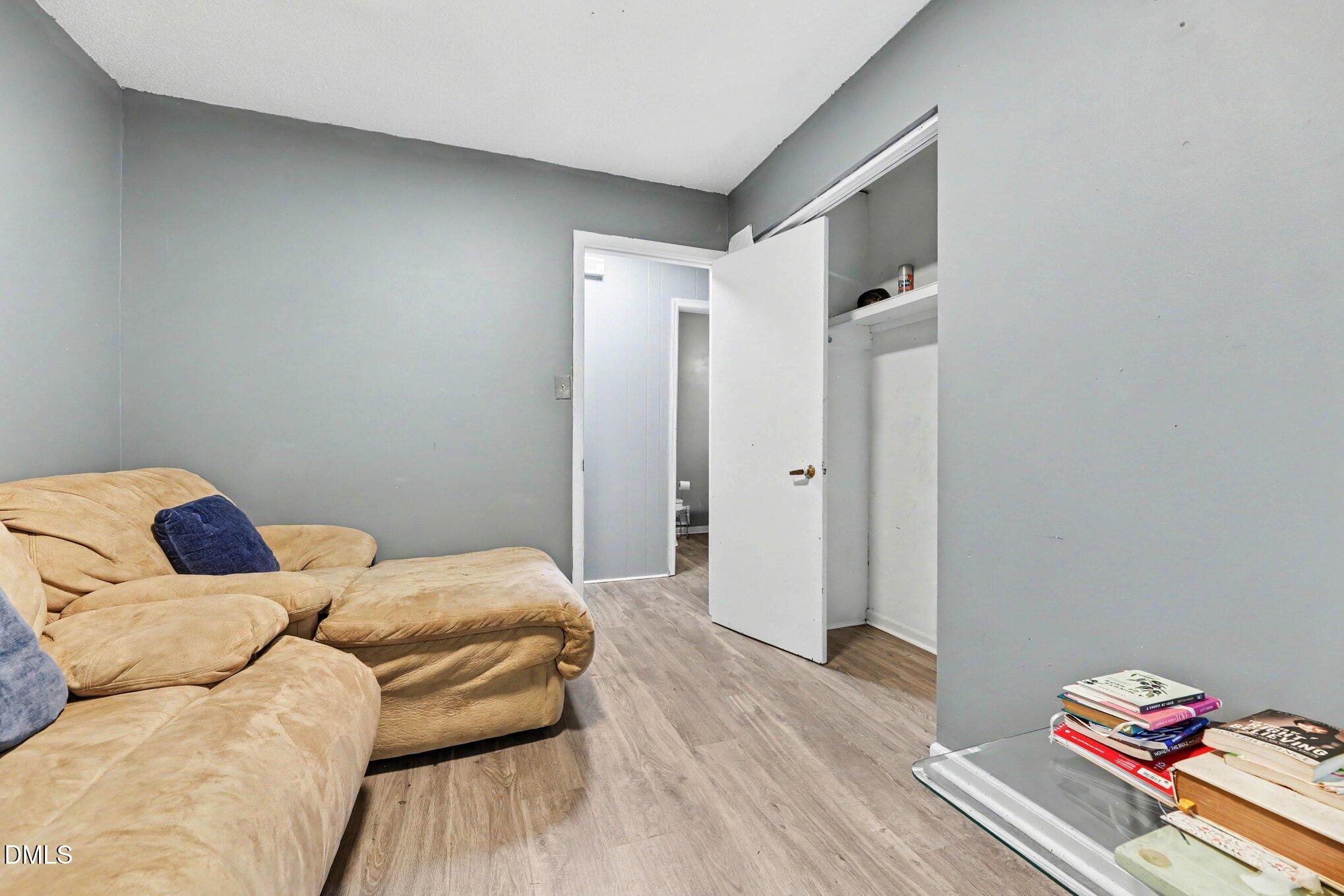 Living room with a tan sectional sofa, gray walls, and an open closet.
