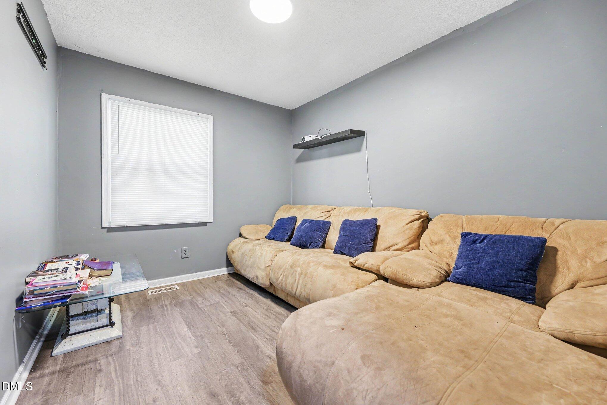 Living room with a large beige sectional, blue pillows, and a glass coffee table.