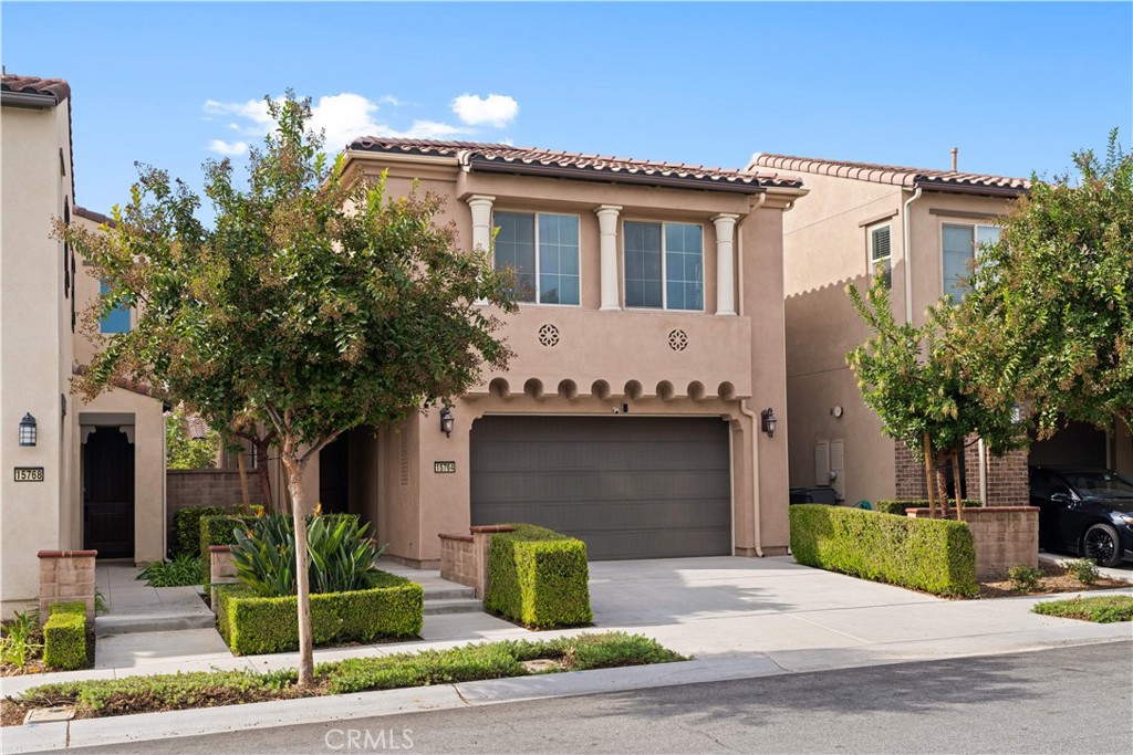 Two-story stucco home with a tiled roof, double garage, and landscaped front yard.