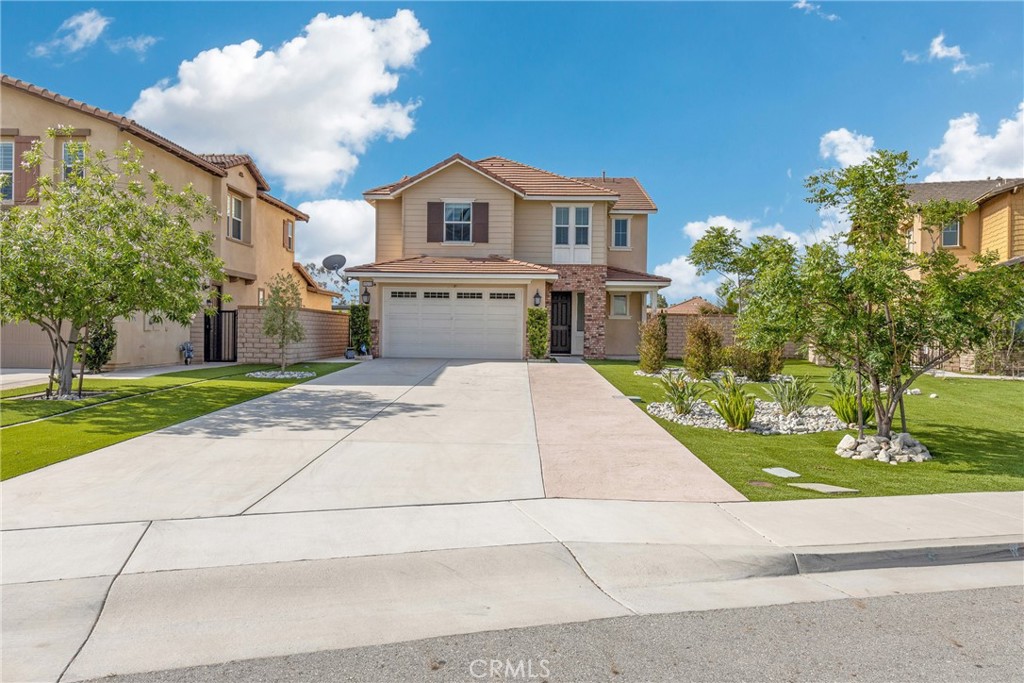 Two-story beige home with a double garage, wide driveway, and landscaped front yard.
