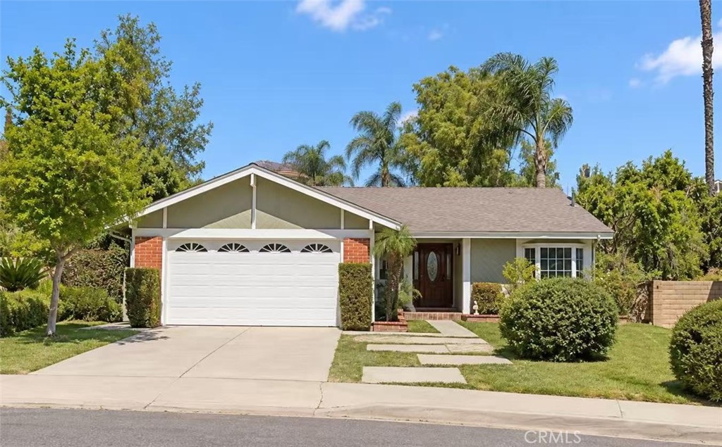 Single-story home with a two-car garage, brick accents, and a landscaped front yard.