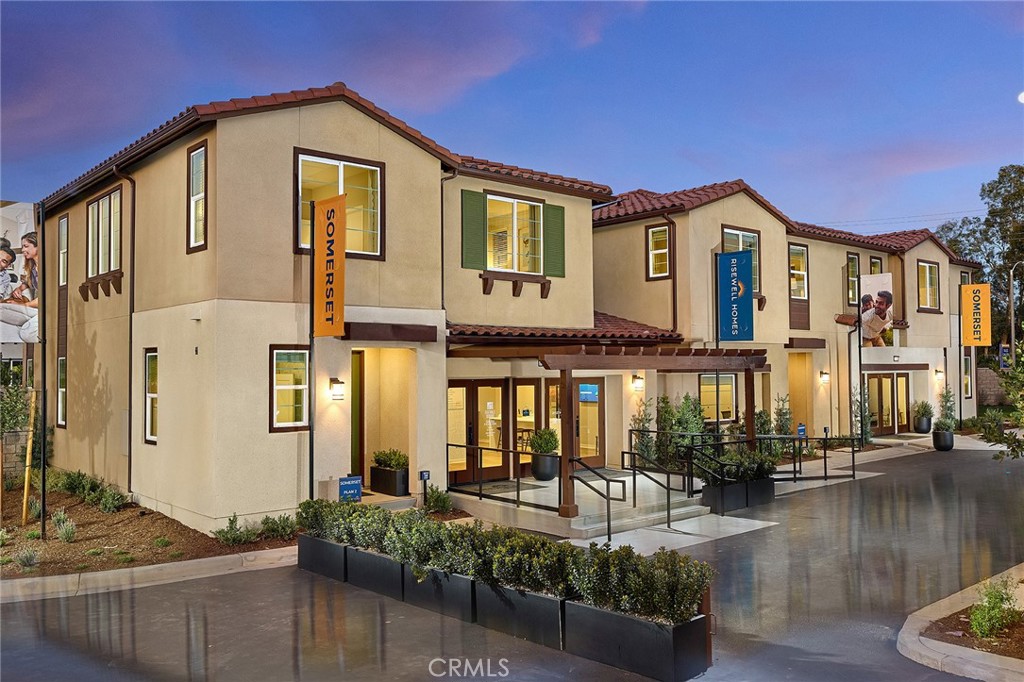 Two-story stucco building with red tile roofs, illuminated windows, and Somerset signs.