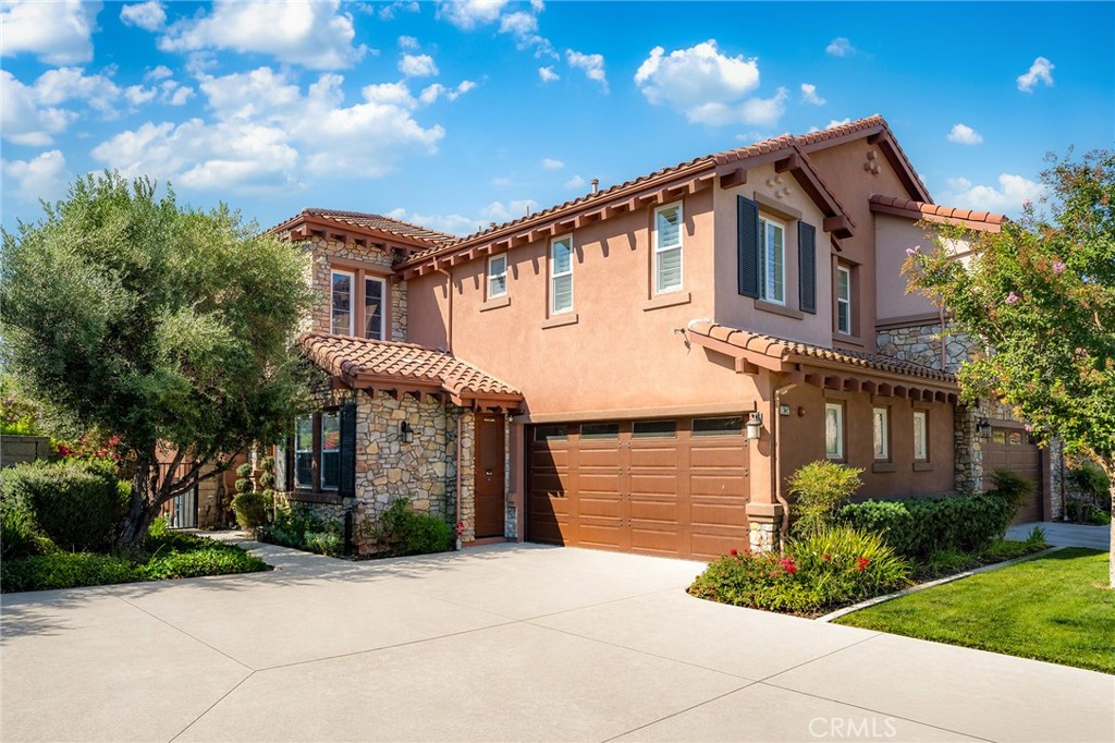 Two-story stucco home with stone accents, terracotta tile roof, and attached double garage.