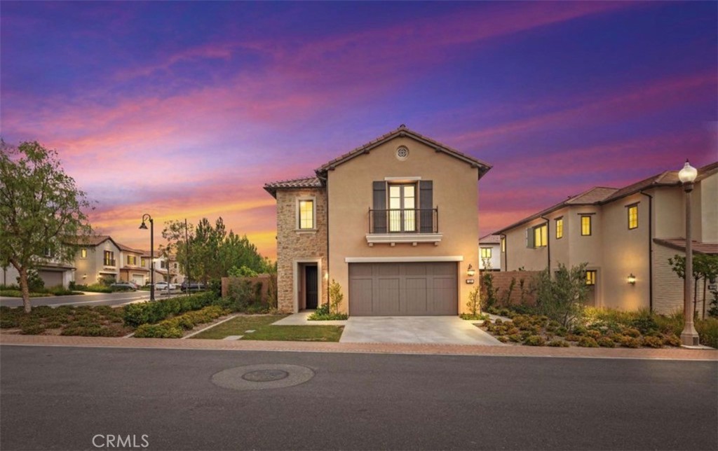 Two-story stucco and stone home with a two-car garage beneath a vivid sunset sky.