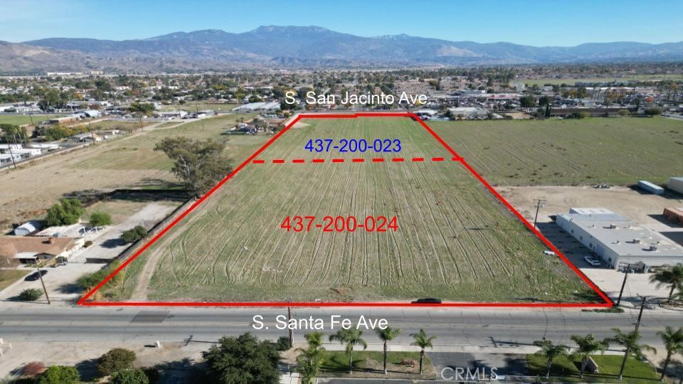 Aerial view of a red-outlined vacant parcel with road frontage and mountains in the distance.