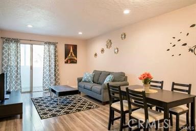 Living and dining room with a gray sofa, geometric rug, and black dining set.