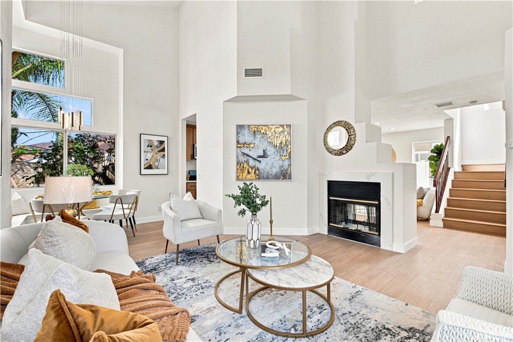 Living room with soaring ceilings, tall windows, a fireplace, and neutral seating.