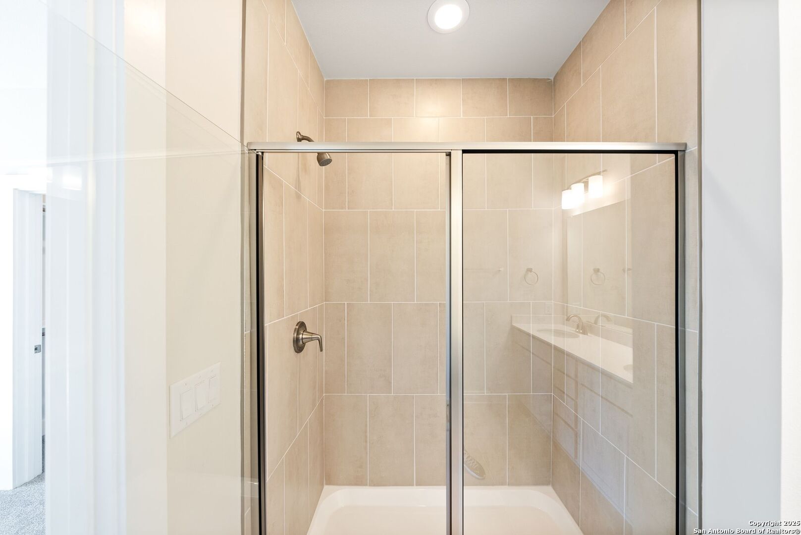 Tiled bathroom with a glass-enclosed bathtub and shower.
