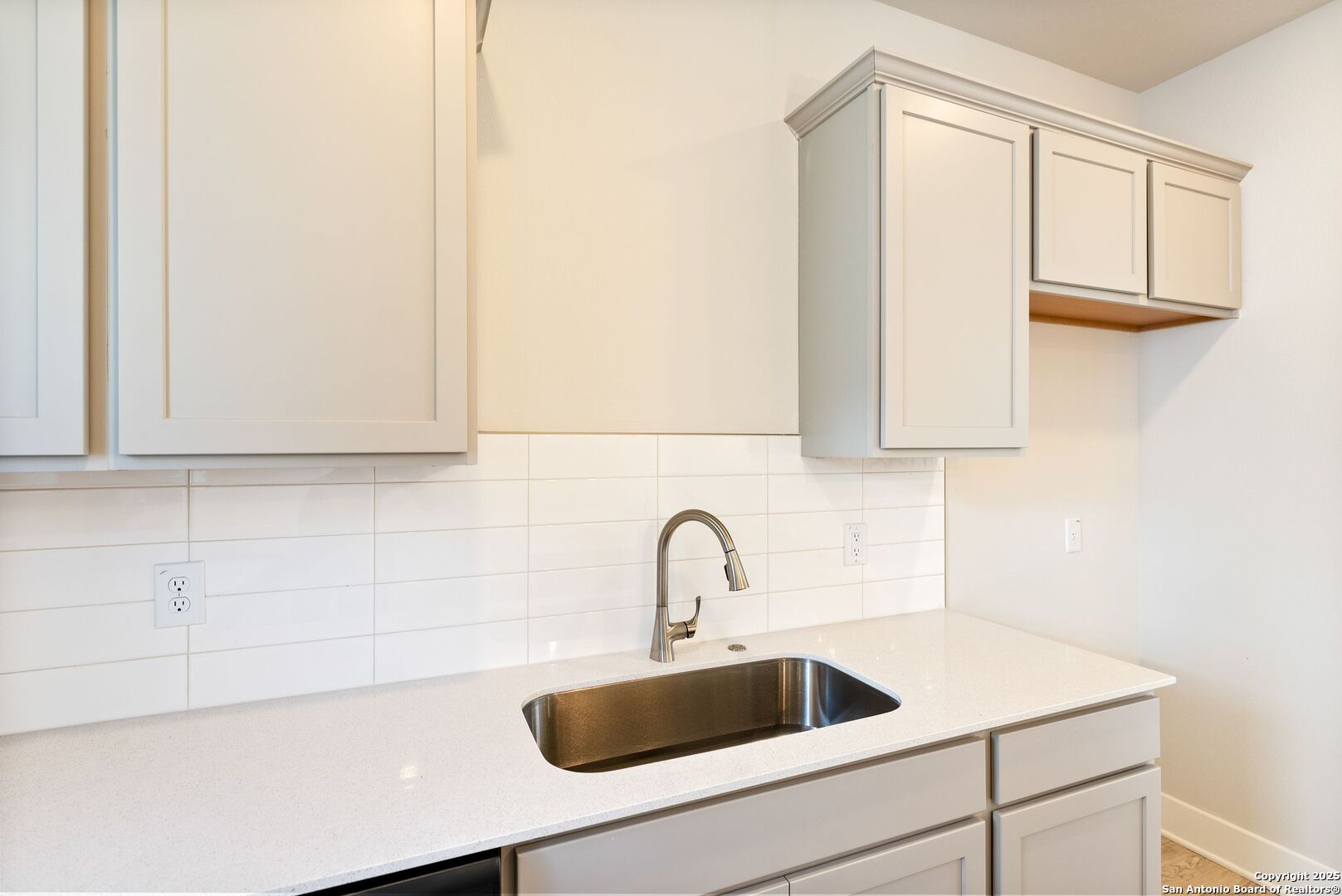 Kitchen with white shaker cabinets, a glossy tile backsplash, and a stainless steel undermount sink.