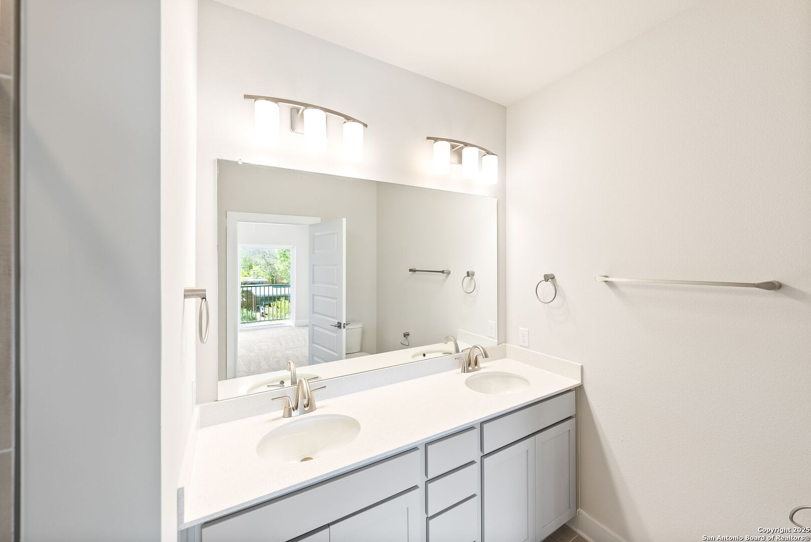 Bathroom with a white double-sink vanity, gray cabinets, and a large mirror.