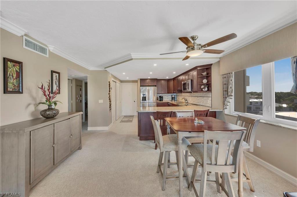 Condo dining area and kitchen with dark wood cabinetry and large windows.