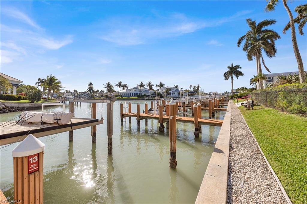 Waterfront marina with wooden docks, a boat lift, and palm trees along a canal.