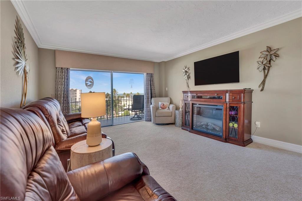Furnished living room with leather sofas, a fireplace, and sliding doors to a balcony.