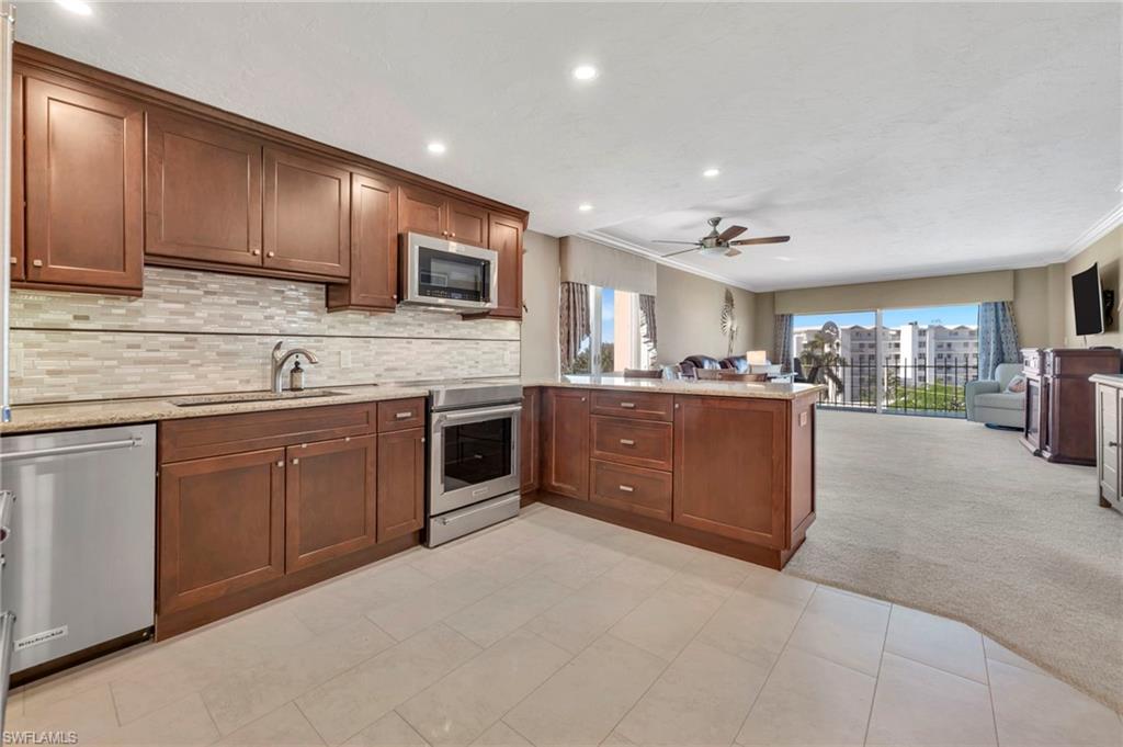 Condo kitchen with cherry cabinets, stainless appliances, and a large island beside the living area.
