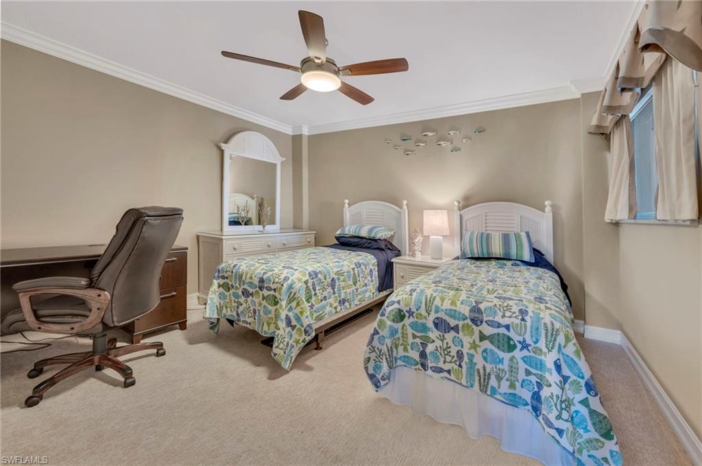 Bedroom with two twin beds in blue-green patterned bedding and a desk with an office chair.