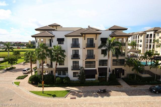 Multi-story condominium building with balconies, palm trees, and landscaped grounds.