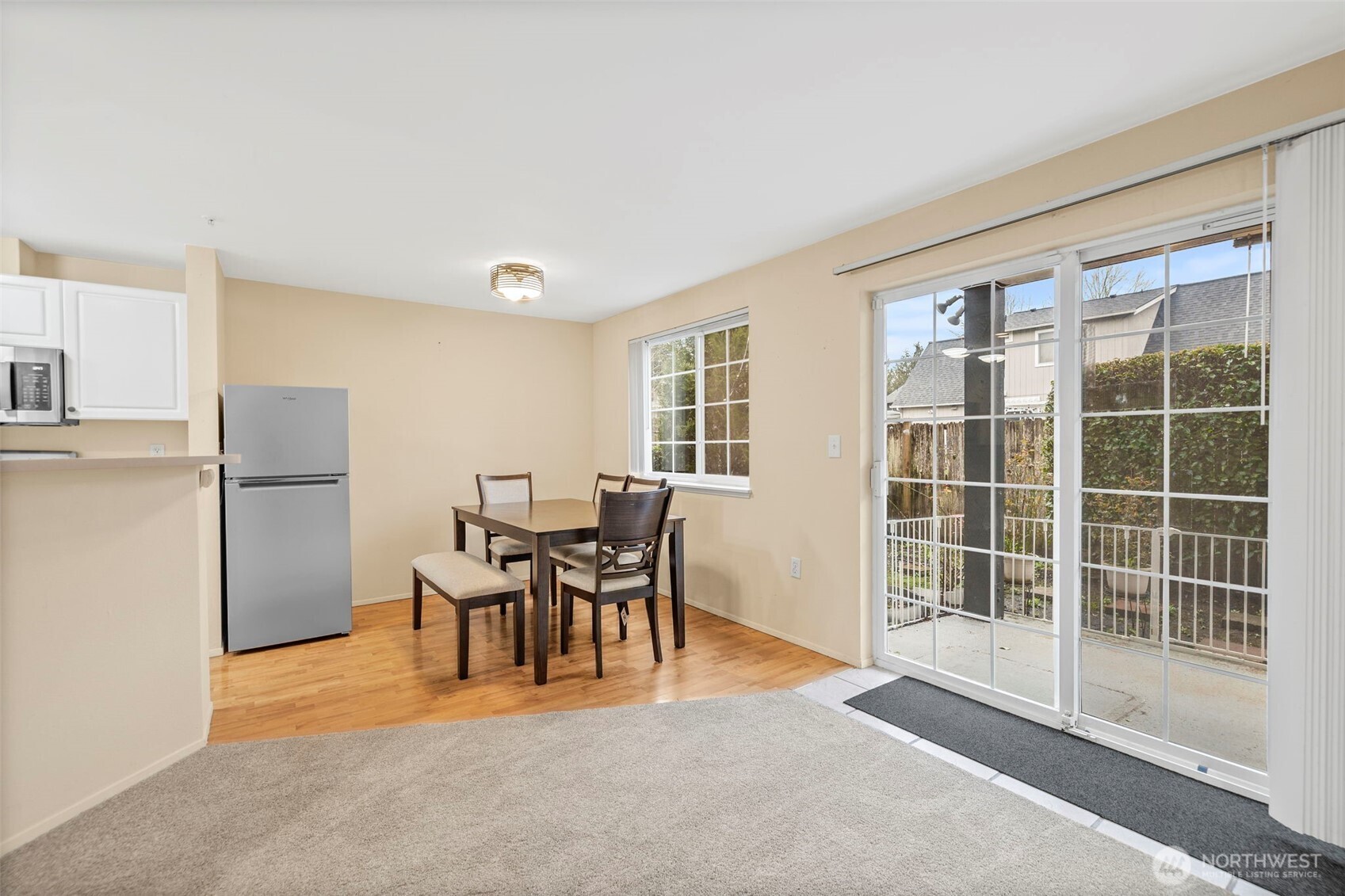 Condo dining area with a wood table, carpeted living space, and sliding glass doors to a patio.