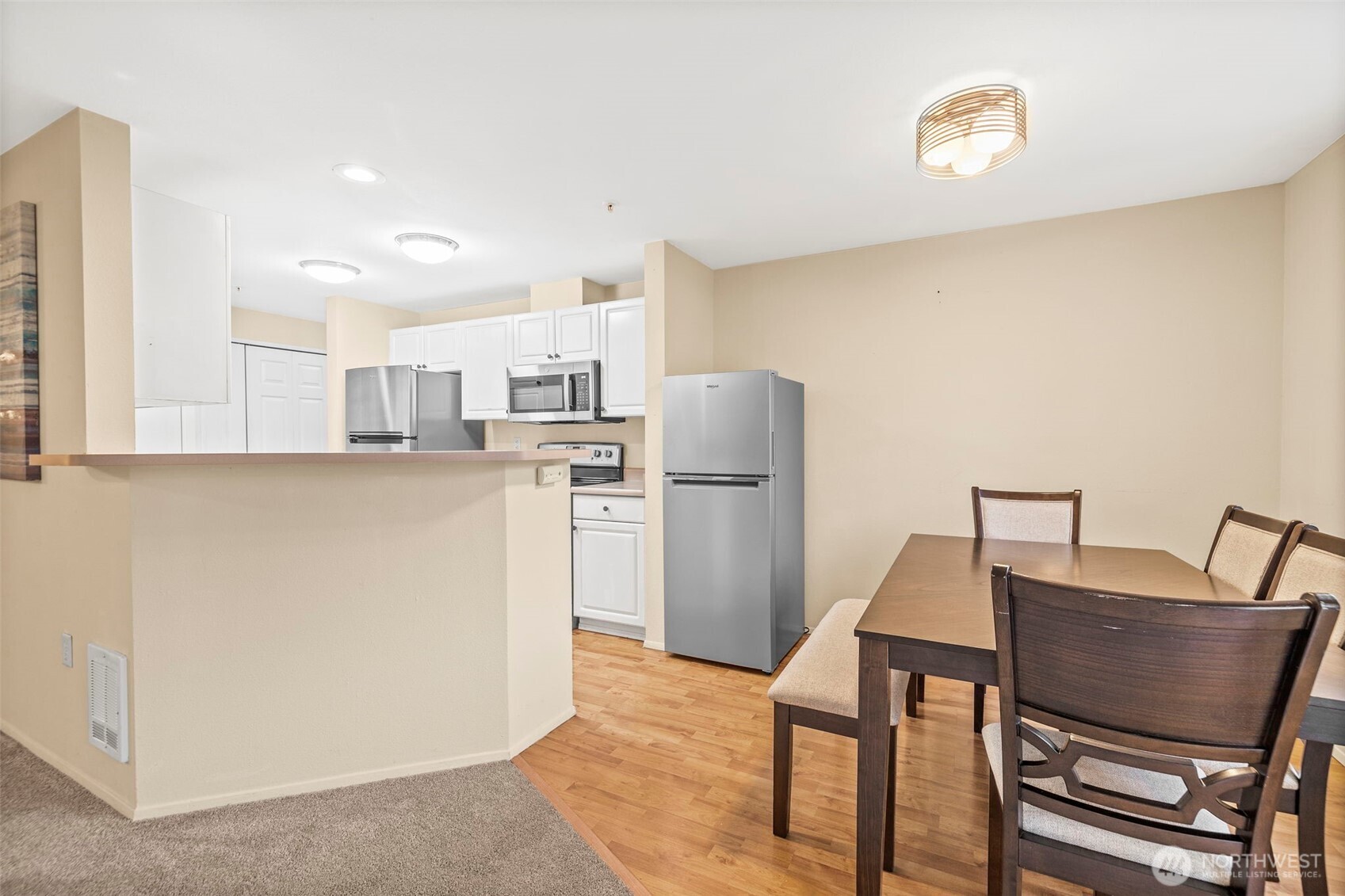 Kitchen and dining area with white cabinets, stainless appliances, and a wood dining set.