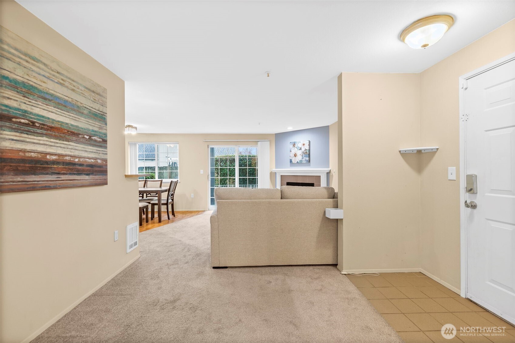 Living room with beige carpet, a fireplace, and sliding glass doors beside the dining area.