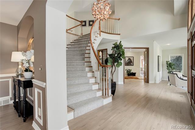 Two-story foyer with a sweeping carpeted staircase, curved wood handrail, and chandelier.