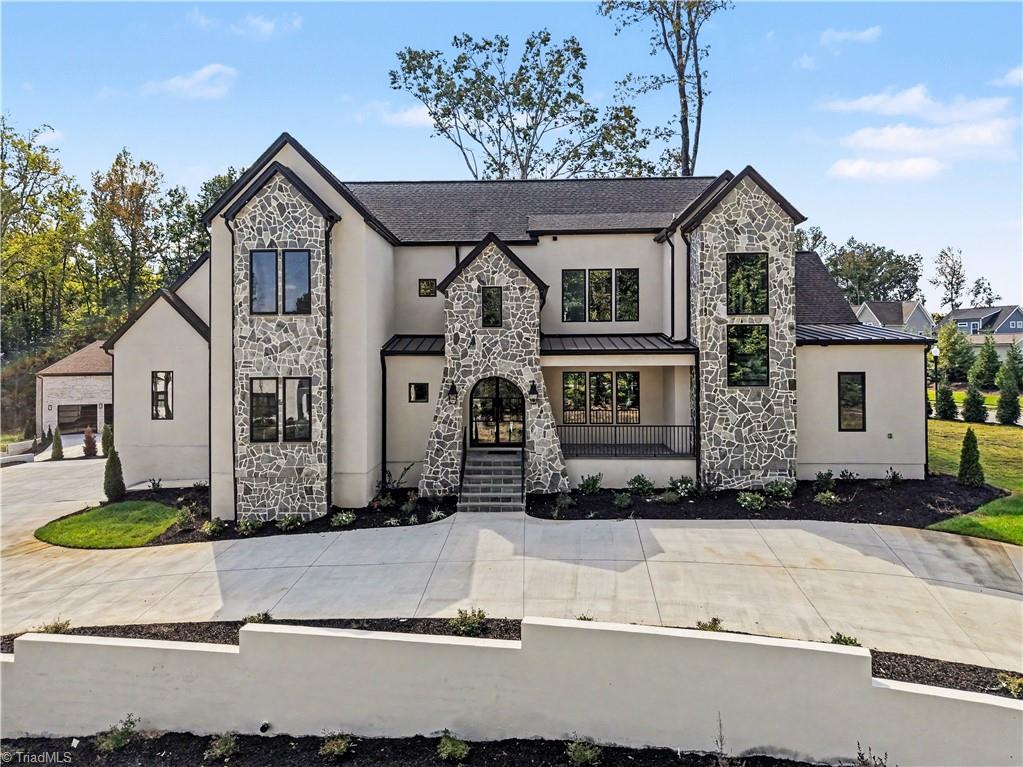 Two-story home with stone-accented towers, an arched entry, and a broad concrete driveway.