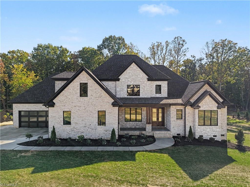 Two-story stone-and-brick home with a dark roof, attached garage, and covered front porch.