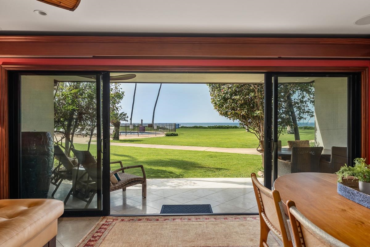 Living and dining area with sliding glass doors overlooking a lawn and the ocean.