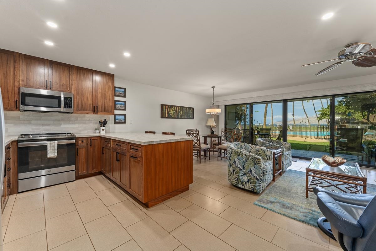 Open-plan kitchen and living room with wood cabinets and sliding doors overlooking the pool and ocean.