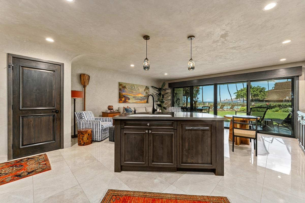Kitchen with a dark wood island and sliding glass doors overlooking a lawn and ocean.