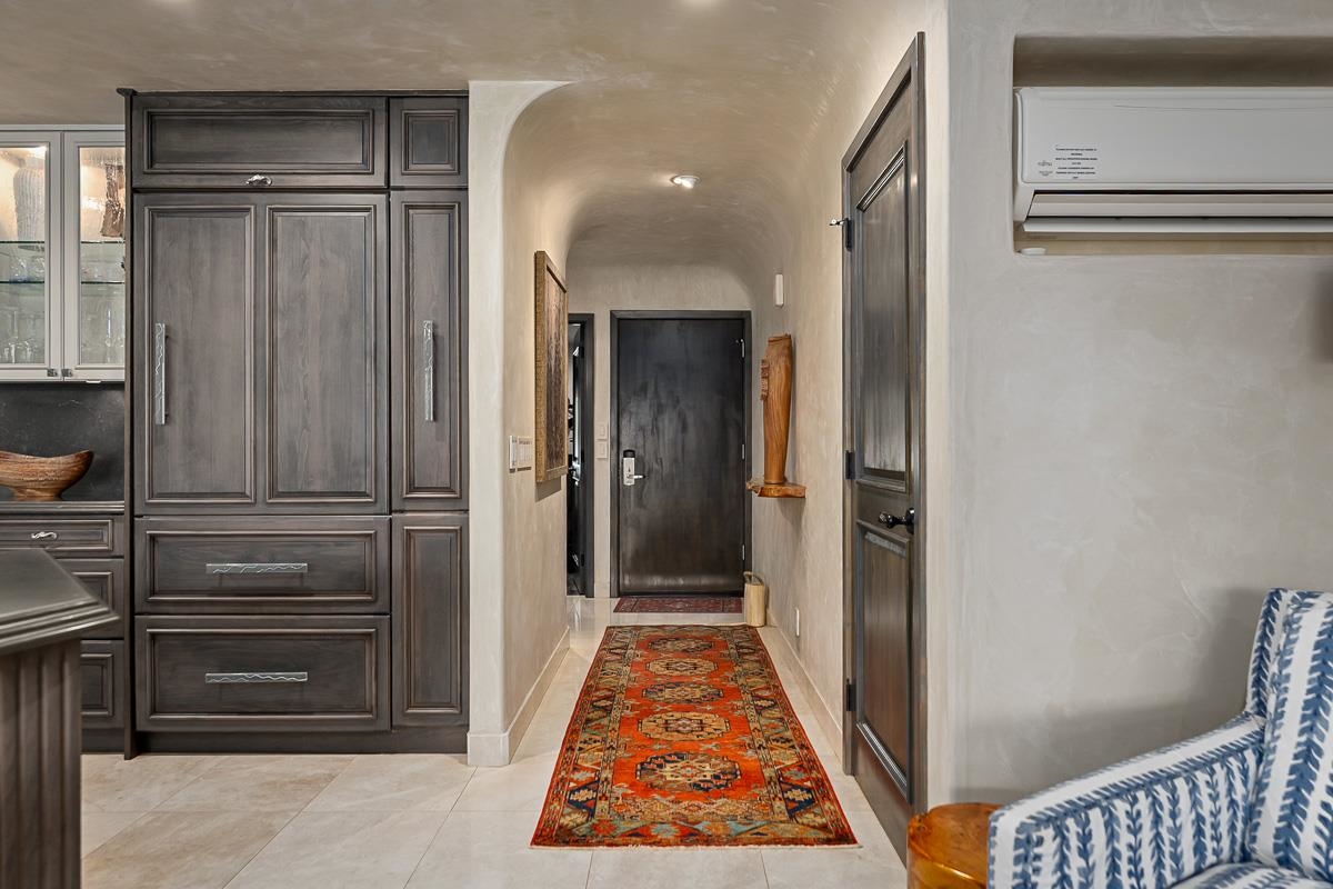Condo entry hallway with dark cabinetry, an orange patterned runner, and a black entrance door.