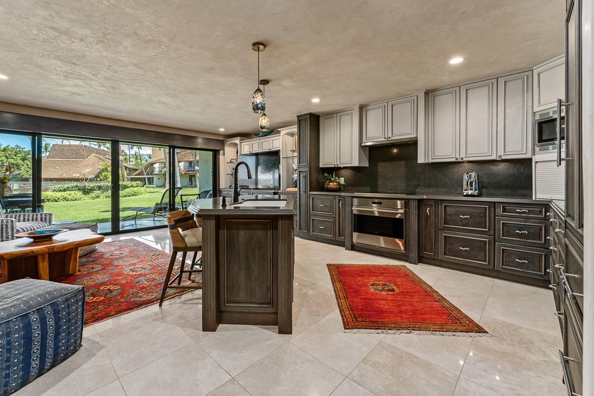 Kitchen with a large island, dark wood cabinetry, and sliding doors overlooking a grassy courtyard.