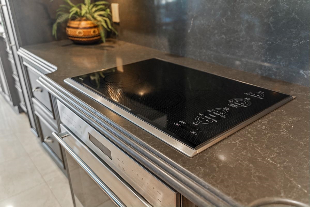Modern kitchen with a black induction cooktop, brown stone counters, and stainless-steel cabinetry.