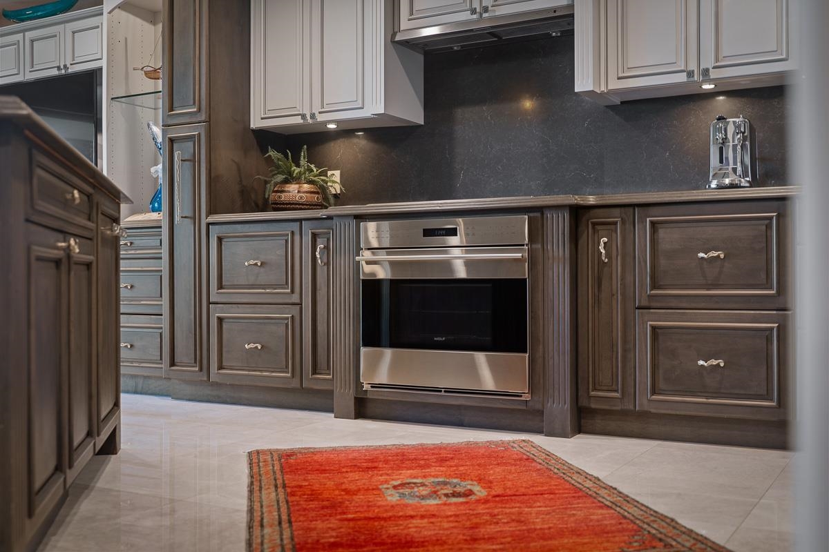 Kitchen with dark paneled cabinets, stainless-steel oven, and red patterned rug.