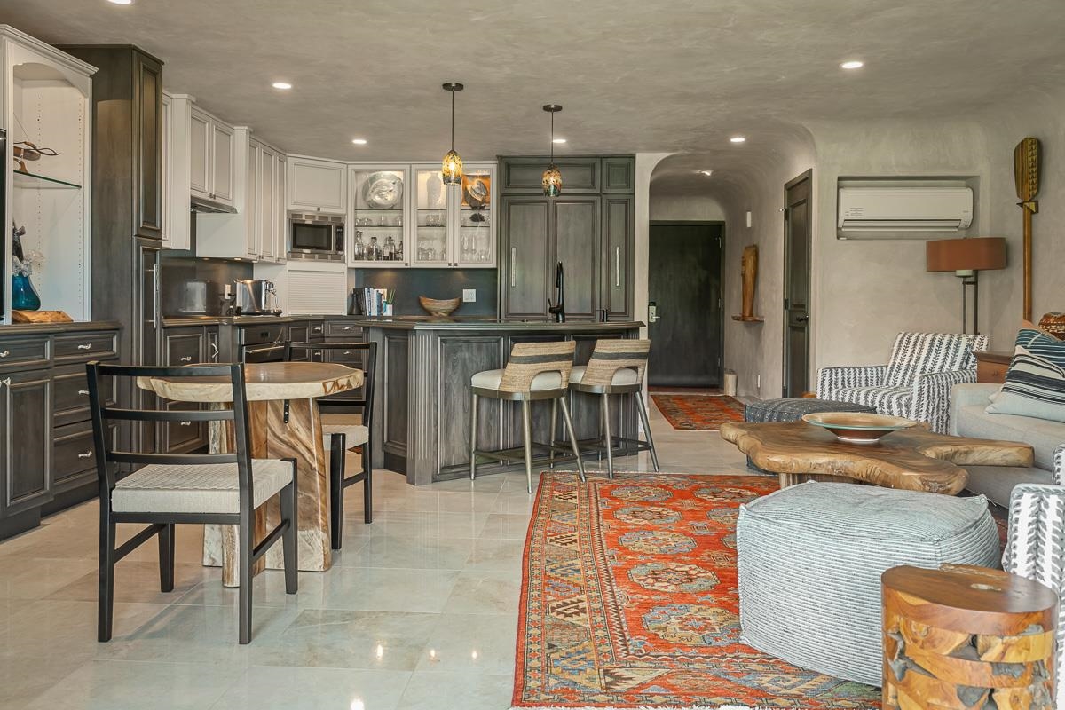Open-plan kitchen and living room with dark cabinetry, breakfast bar, and colorful patterned rug.