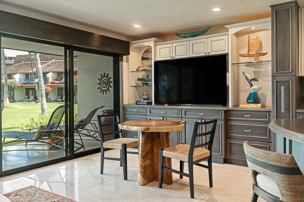 Condo living and dining area with built-in media cabinets and sliding doors to a landscaped courtyard.