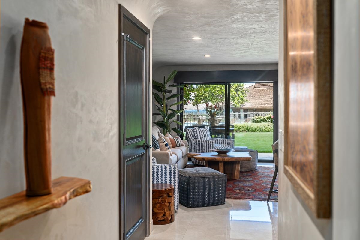 Furnished living room with patterned seating and sliding doors overlooking a lawn and water.