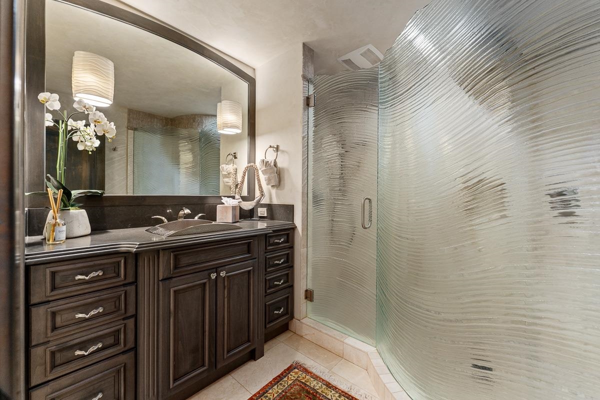 Bathroom with a dark wood vanity and curved textured-glass shower enclosure.