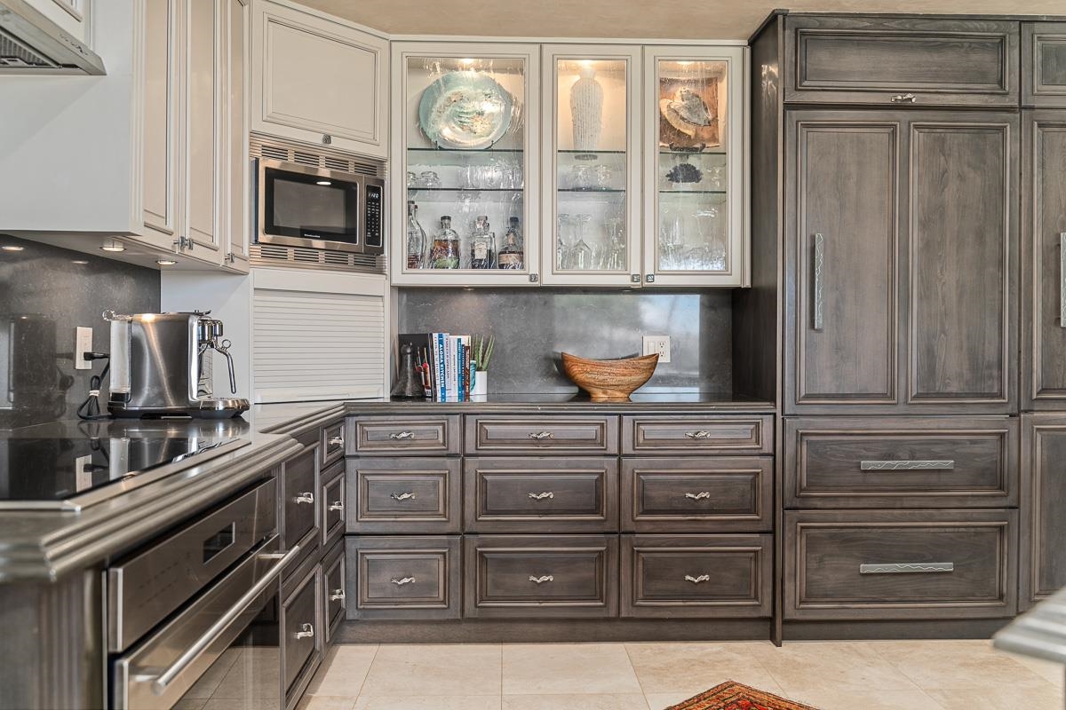 Kitchen with dark wood cabinets, glass-front display cupboards, and stainless steel appliances.