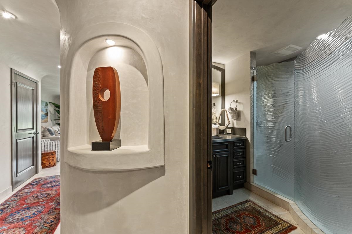 Bathroom with a textured glass shower, dark vanity, and arched display niche.